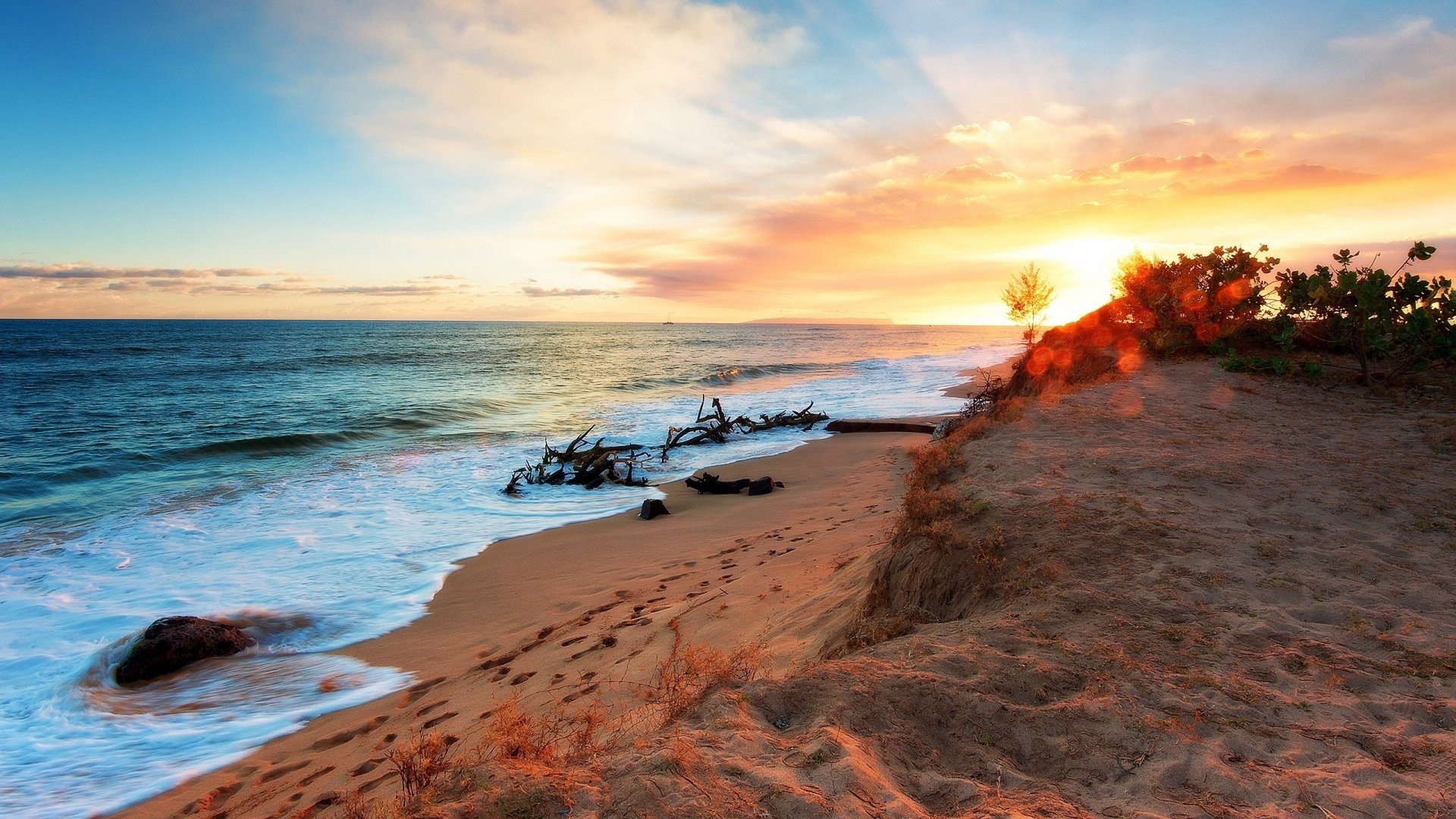 A serene coastline at sunrise, featuring golden sand, gentle waves of the ocean, and vibrant clouds, creating a picturesque scene of nature's beauty.