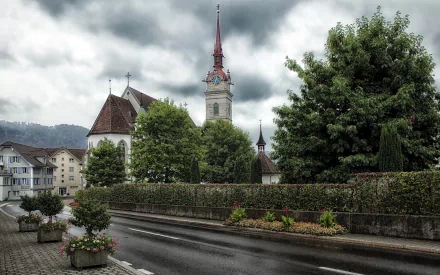 A serene church framed by lush greenery and colorful flowers, set against a dramatic cloudy sky, creating a peaceful religious atmosphere. HD wallpaper and background.