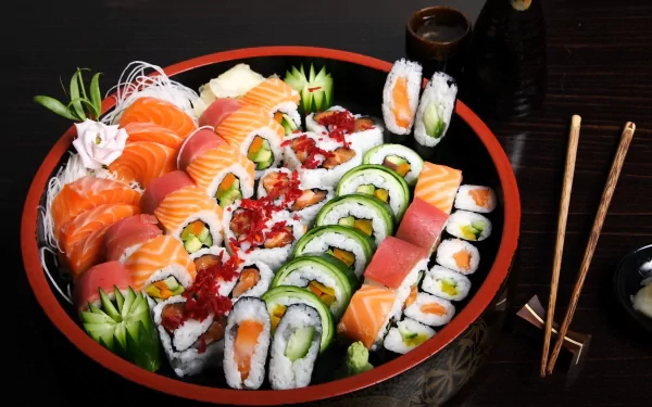 HD desktop wallpaper featuring a vibrant platter of assorted sushi rolls and sashimi, accompanied by chopsticks, soy sauce, and wasabi on a dark wooden table.