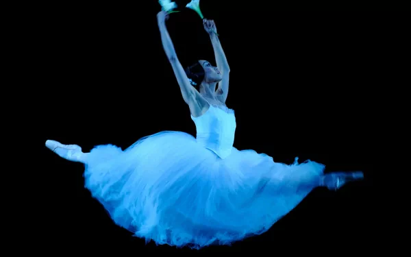HD PC desktop wallpaper of a woman in mid-air performing an elegant ballet leap, dressed in a flowing white tutu against a dark background.