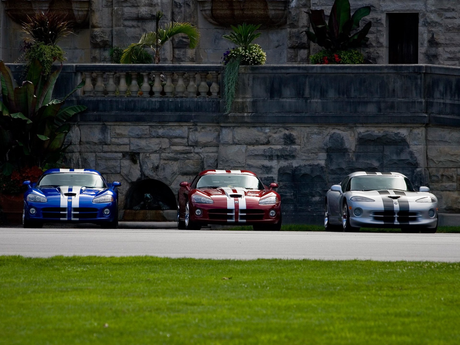 HD PC desktop wallpaper background: three Dodge Viper sports cars — blue, red, silver — lined up on a road before an ornate stone wall.