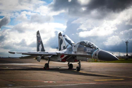 A Sukhoi Su-27 military aircraft parked on the tarmac, under a dramatic sky. This HD image showcases the power and design of modern air force technology.