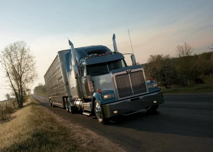 HD desktop wallpaper of a Western Star vehicle driving on a rural road during sunset with trees and open fields in the background.