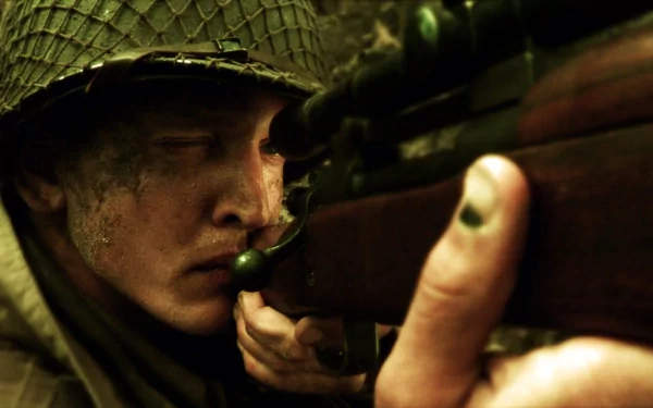 A soldier with a focused expression peers through the scope of a rifle, capturing the intense atmosphere of Saving Private Ryan. This HD wallpaper evokes the film's gripping wartime tension.