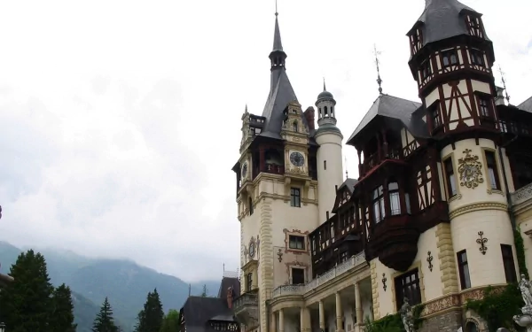 HD PC desktop wallpaper/background of Peles Castle, Romania — a dramatic man-made Neo-Renaissance castle set against misty Carpathian mountains.