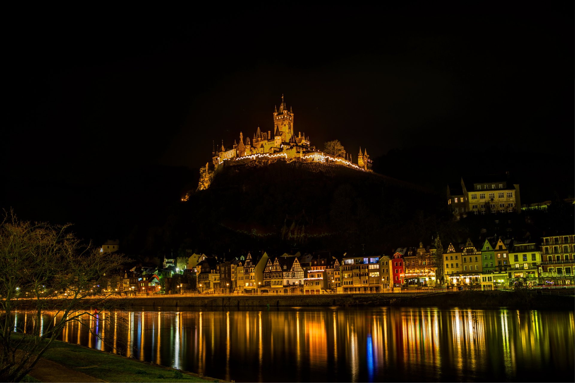Cochem Castle illuminated at night atop a hill, overlooking the town and river, captured in 4K Ultra HD as a striking man-made architectural landmark.