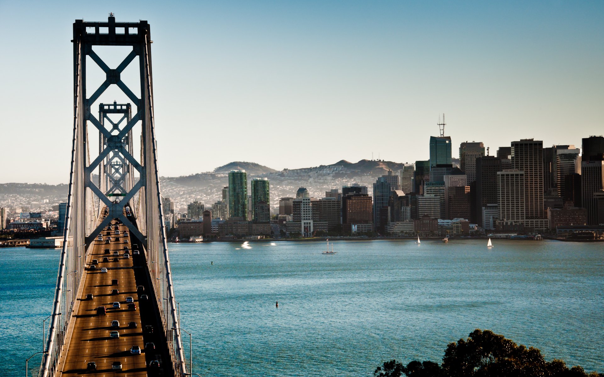 HD wallpaper of the Bay Bridge with the San Francisco skyline in the background, showcasing the man-made architectural marvel against clear blue water and sky.