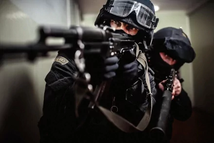 A dramatic HD wallpaper featuring armed SWAT team members in tactical gear, poised and focused as they navigate a corridor, embodying intensity and precision in a military context.