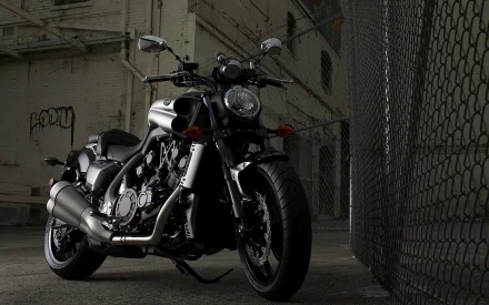 HD PC desktop wallpaper of a Yamaha V-Max motorcycle parked in an industrial garage, dramatic low-light shadows and a chain-link fence background.