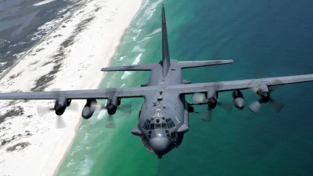 HD desktop wallpaper of a Lockheed AC-130 military aircraft flying over a coastal shoreline with clear waters and sandy beaches.