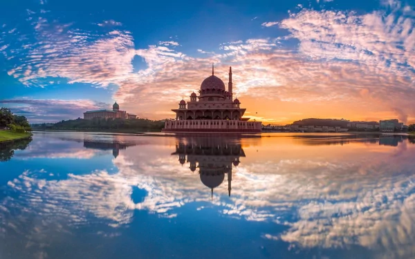 HD desktop wallpaper featuring a serene view of the Putra Mosque at sunset, reflected in calm waters under a vibrant, colorful sky.