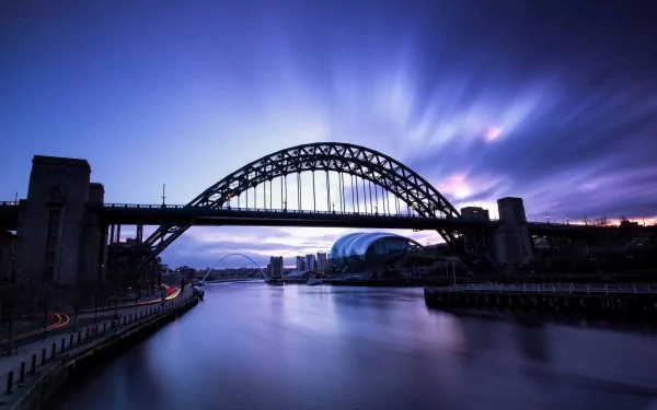 HD PC desktop wallpaper of the Tyne Bridge, a man-made steel arch spanning the River Tyne at dusk, long-exposure sky and glassy water reflecting city lights.