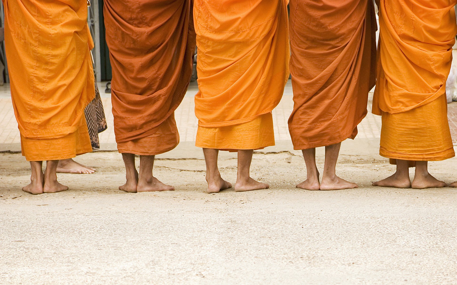 HD desktop wallpaper showing the feet and robes of Buddhist monks standing in a row, highlighting religious tradition and simplicity.