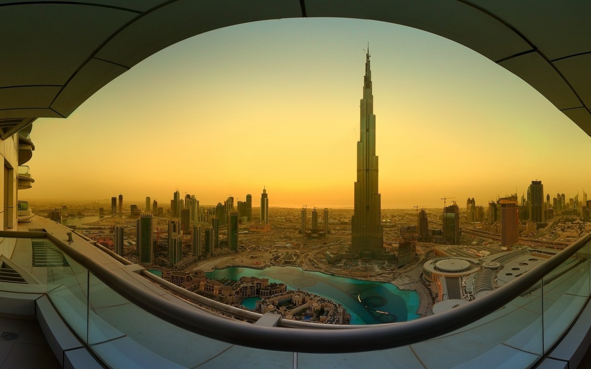 HD desktop wallpaper showcasing the man-made skyline of Dubai at sunset, featuring the iconic Burj Khalifa framed by an architectural structure.