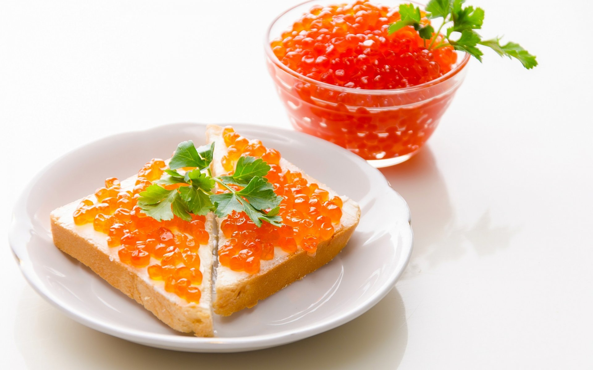 HD PC desktop wallpaper featuring a close-up of a sandwich topped with orange caviar and garnished with parsley, alongside a small bowl of caviar on a white plate.