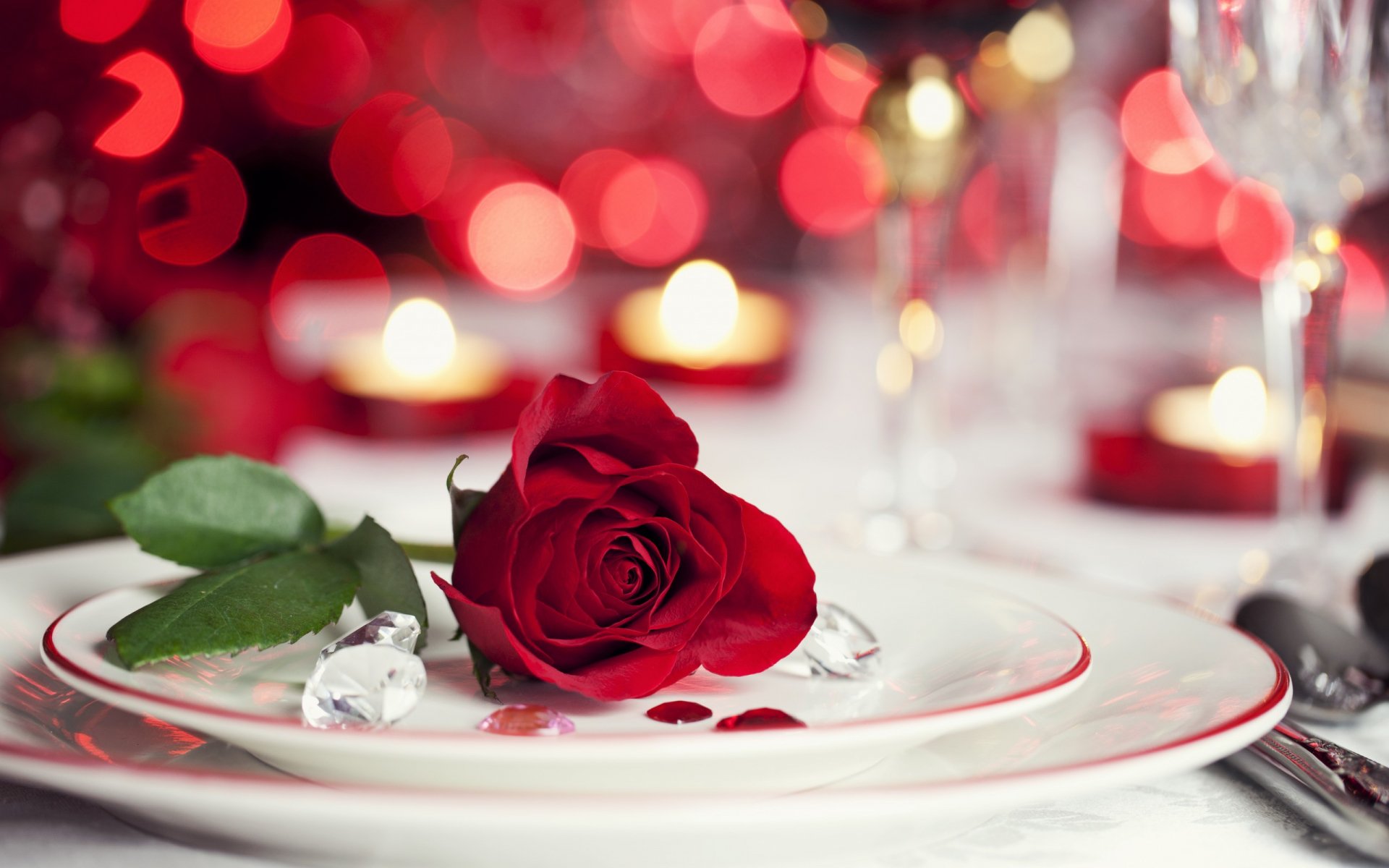 HD Valentine's Day desktop wallpaper featuring a single red rose on a white plate, surrounded by glass hearts and blurred red and gold holiday lights.