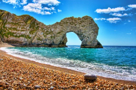 4K Ultra HD wallpaper capturing the natural beauty of Durdle Door, a stunning coastal rock formation against a vibrant blue sky and pebbled beach.