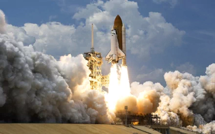 Space Shuttle Atlantis vehicle launching amid smoke and flames — dramatic 2K Quad HD PC desktop wallpaper background.