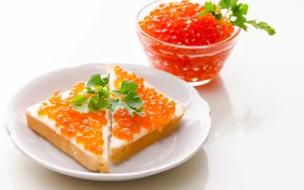HD PC desktop wallpaper featuring a close-up of a sandwich topped with orange caviar and garnished with parsley, alongside a small bowl of caviar on a white plate.