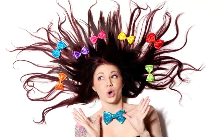 2K Quad HD PC desktop wallpaper of a surprised woman with hair fanned out, colorful bows woven through her strands and a glittery blue bow tie.