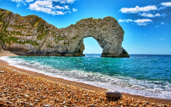 4K Ultra HD wallpaper capturing the natural beauty of Durdle Door, a stunning coastal rock formation against a vibrant blue sky and pebbled beach.