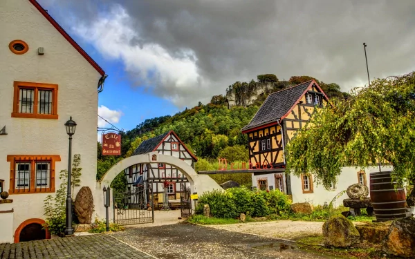 HD desktop wallpaper featuring a charming man-made village with traditional half-timbered houses, cobblestone streets, and lush greenery under a cloudy sky.
