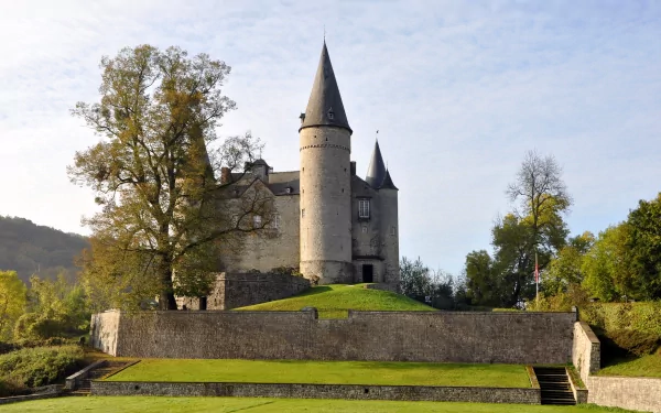 HD desktop wallpaper featuring the man-made Castle of Vêves surrounded by greenery under a clear sky.