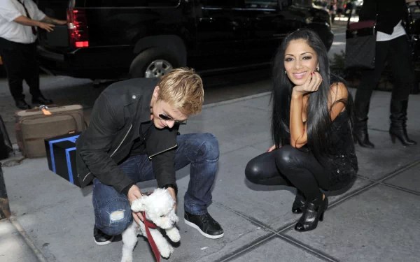 HD PC desktop wallpaper featuring Nicole Scherzinger smiling and posing on a sidewalk next to a person crouching and interacting with a small white dog.