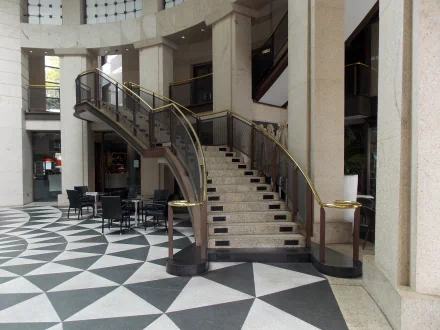 A sleek interior scene in Circular Quay, Sydney, featuring a curved staircase and geometric tile flooring, showcasing modern architecture with stylish seating arrangements.