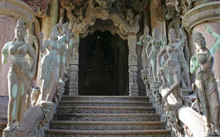 Ancient intricately carved stone statues and ornate doorway at a Buddhist temple, captured in a high-definition PC desktop wallpaper.