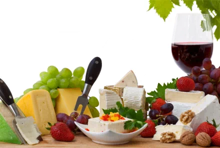 A vibrant 4K Ultra HD desktop wallpaper featuring an assortment of cheeses, green and red grapes, strawberries, walnuts, and a glass of red wine on a white background.