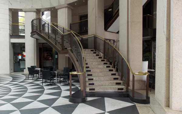 A sleek interior scene in Circular Quay, Sydney, featuring a curved staircase and geometric tile flooring, showcasing modern architecture with stylish seating arrangements.
