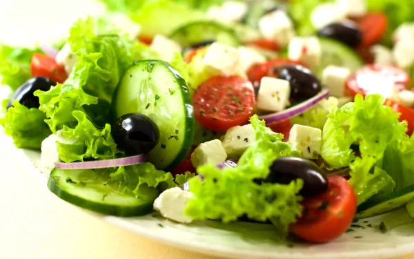 HD PC desktop wallpaper showing a fresh salad with lettuce, cucumber slices, cherry tomatoes, black olives, red onion, and feta cheese cubes.