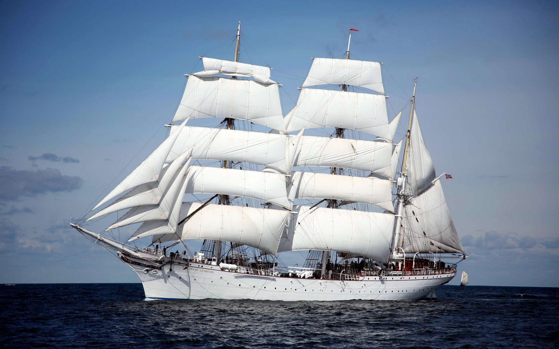 HD PC desktop wallpaper of a white sailboat vehicle with full sails gliding across a calm blue sea under a pale sky