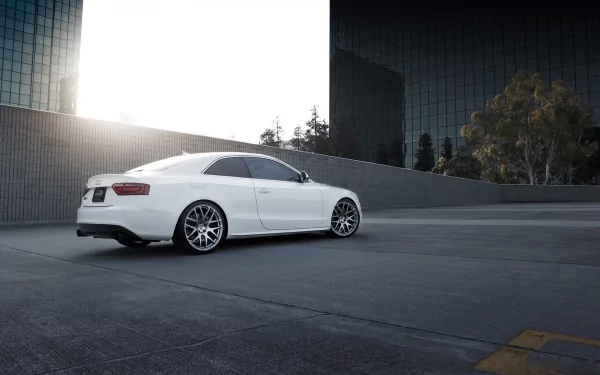 HD PC desktop wallpaper featuring a sleek white Audi S5 parked in an urban setting with modern glass buildings and bright sunlight.