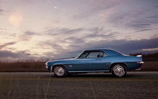 HD PC desktop wallpaper featuring a blue Chevrolet Camaro SS parked on a road under a cloudy sky at dusk.