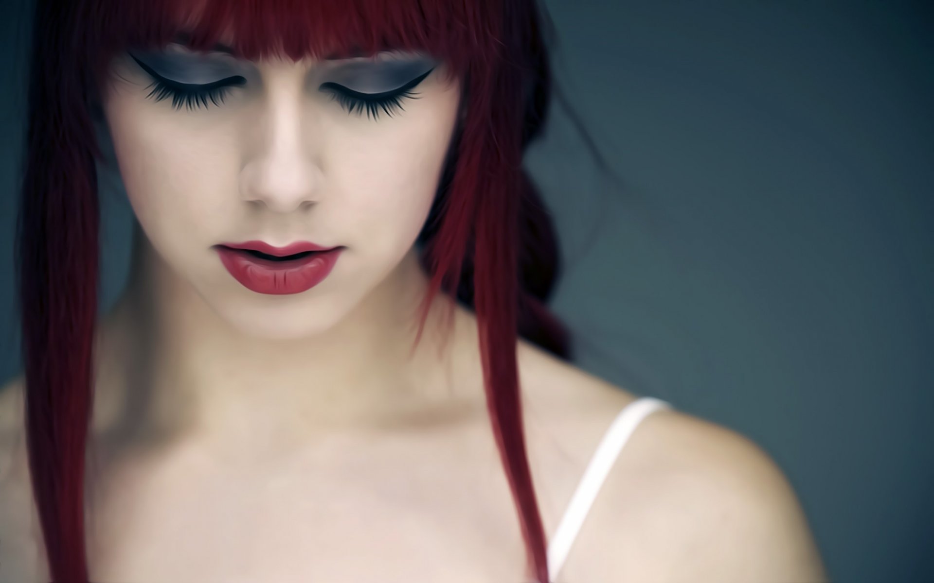 HD PC desktop wallpaper featuring a close-up of a woman’s face with red hair, closed eyes, and bold makeup against a soft, blurred background.