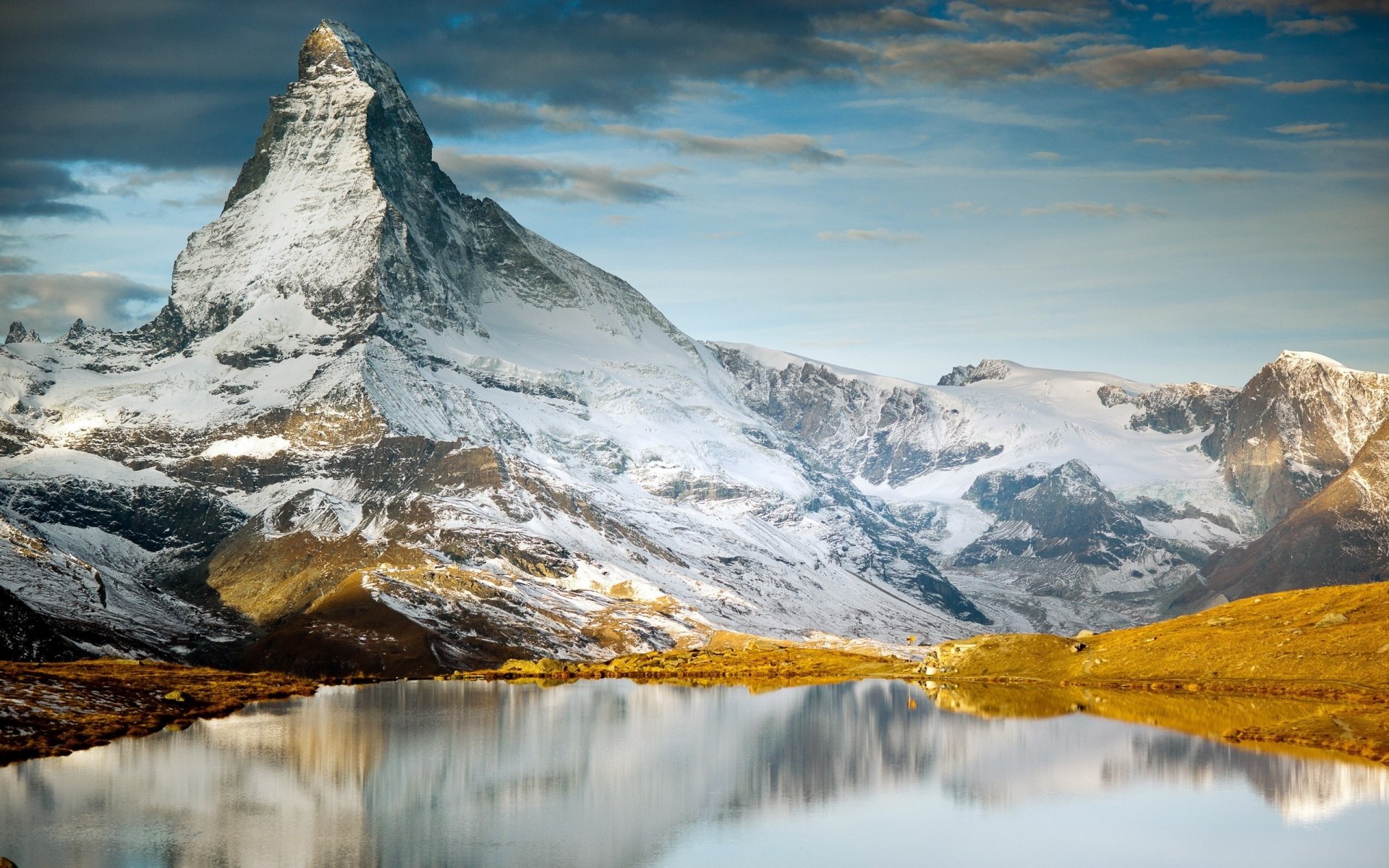 HD PC desktop wallpaper showcasing a majestic snow-capped mountain reflected in a calm lake under a partly cloudy sky, highlighting the beauty of nature and mountainous landscapes.