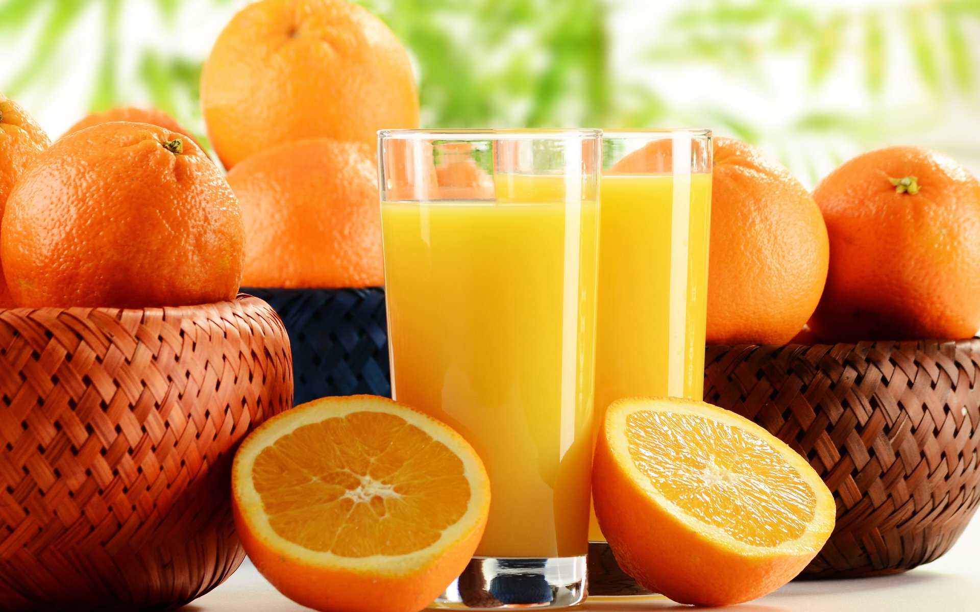 HD desktop wallpaper featuring vibrant orange-colored oranges and two glasses of fresh orange juice against a soft, natural background.