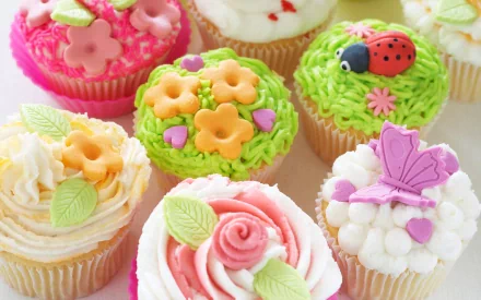 A vibrant assortment of decorated cupcakes, each topped with colorful frosting, flowers, and playful designs, creating a delightful food-themed HD PC desktop wallpaper.