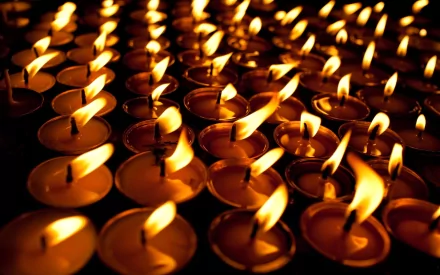 HD PC desktop wallpaper featuring a close-up photograph of numerous glowing candles with flickering flames creating a warm, serene ambiance.