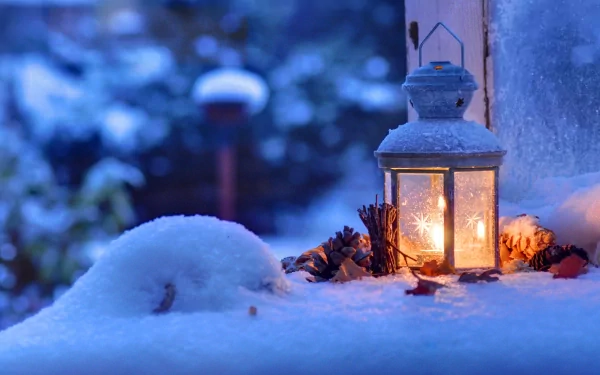 A snowy scene with a glowing lantern, pine cones, and Christmas decor, creating a cozy holiday atmosphere. This HD desktop wallpaper and background captures the magic of Christmas in a serene winter setting.