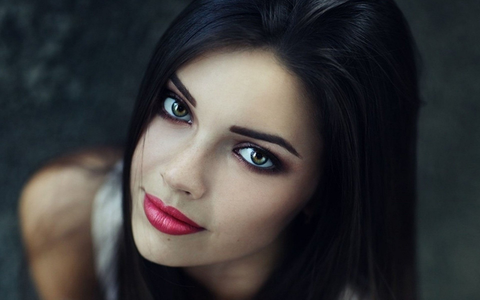 HD desktop wallpaper featuring a woman's face, highlighting her striking blue eyes and red lips against a blurred background.