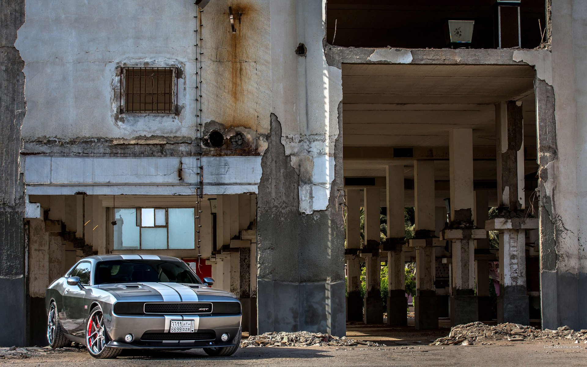HD desktop wallpaper featuring a Dodge Challenger SRT parked inside a weathered, abandoned industrial building with concrete pillars and peeling walls.