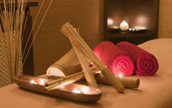 A serene spa setting featuring rolled towels, candles, and bamboo elements, creating a peaceful ambiance for relaxation. High-definition desktop wallpaper and background.