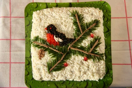 Square salad on a green plate with shredded white topping, spruce sprigs, red berries and a red-black bird decoration — food, salad; 2K Quad HD PC desktop wallpaper background.