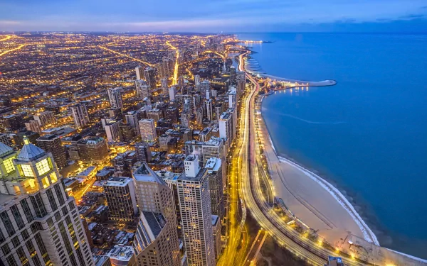 A high-definition desktop wallpaper showing the man-made cityscape of Chicago at dusk, with illuminated streets along the shoreline.