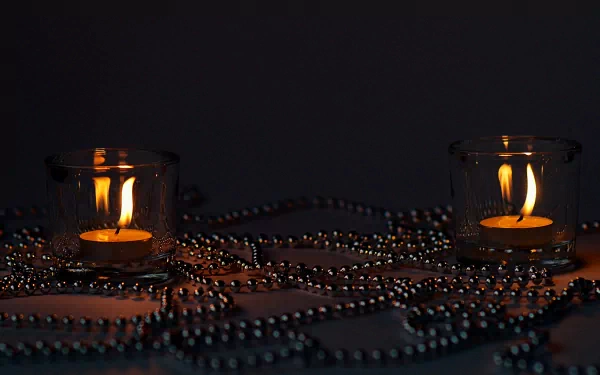HD photography of two lit candles in glass holders surrounded by metallic beads on a dark surface, designed as a PC desktop wallpaper and background.