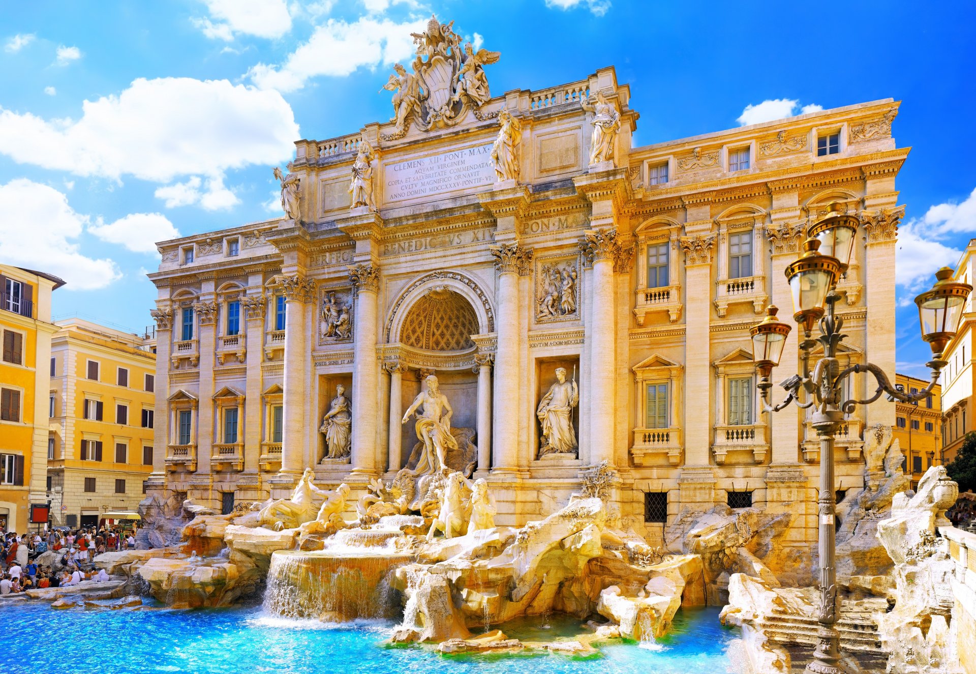 A stunning view of the Trevi Fountain in Rome, showcasing its grand statue and elaborate architecture against a bright blue sky, capturing the essence of Italy's historic beauty.