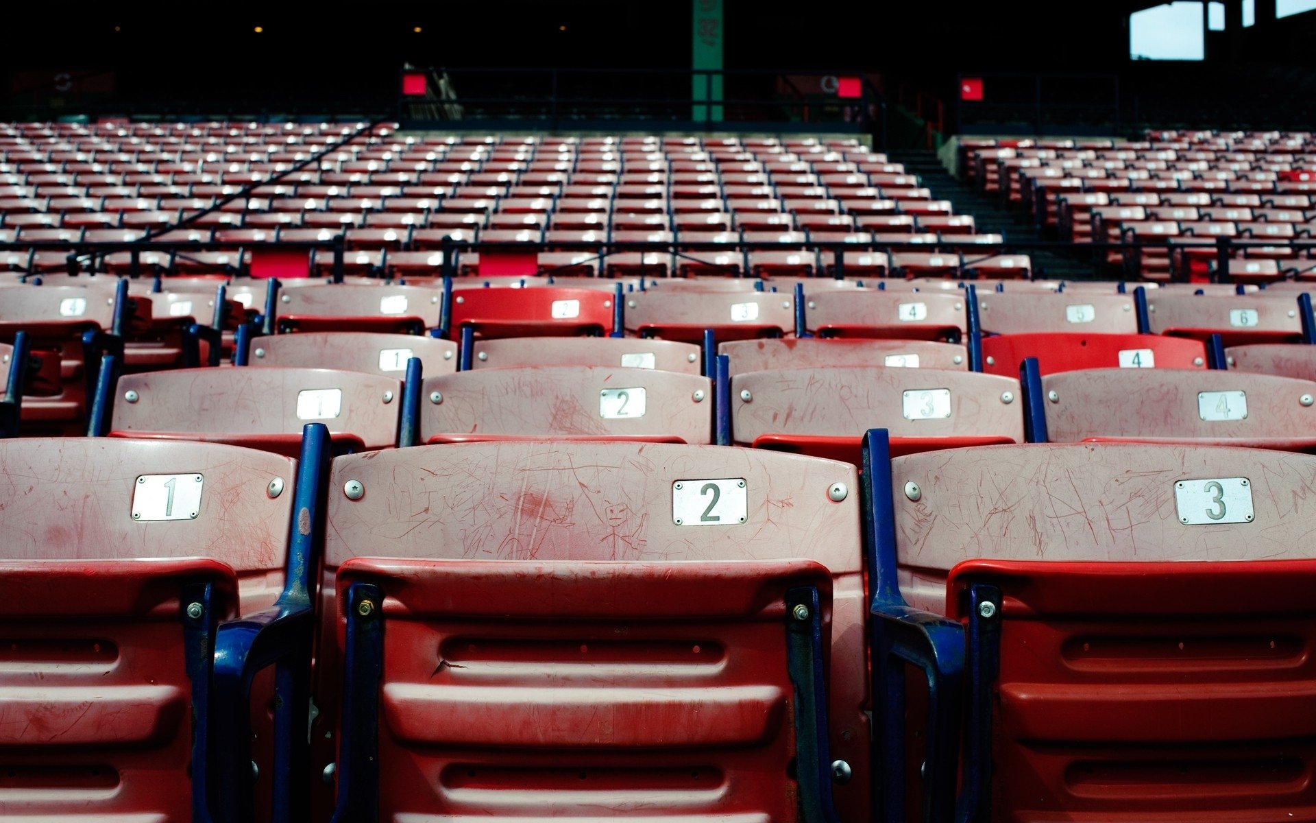 HD PC desktop wallpaper and background: empty stadium sports seating—rows of worn red numbered seats in repeating perspective.